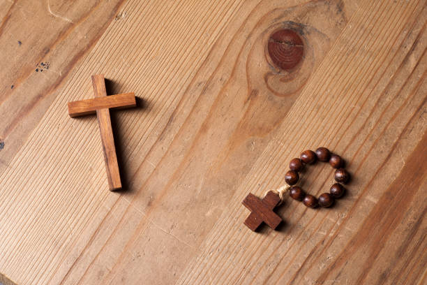 istock Cross and rosary over wood table with window light 1163642463