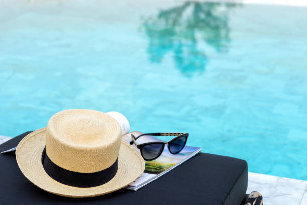 istock Book and hat on the sun bed near the swimming pool, 1163644721