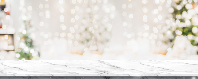 Christmas background of marble table top with abstract warm living room decor with christmas tree string light blur bokeh with snow,Holiday backdrop, panoramic Mock up banner for display of product