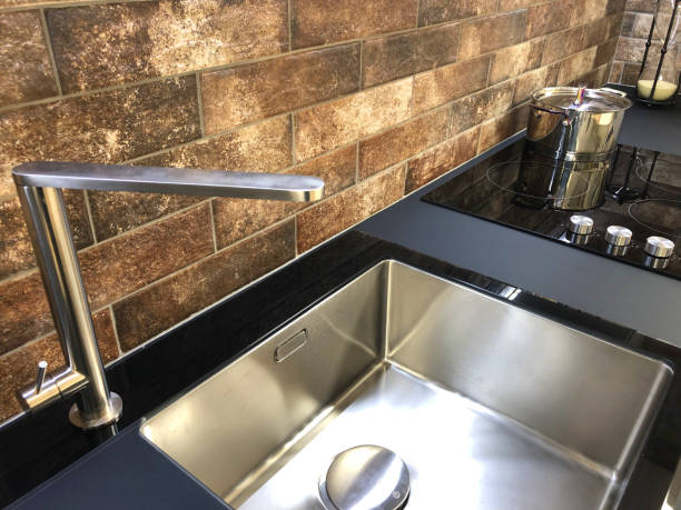 image of rectangular kitchen butler sink, white stainless stee sink with black granite worktop countertop and composite modern induction ceramic hob / black kitchen cooker stove electric hot plate zones with touch control knobs - pipe range imagens e fotografias de stock