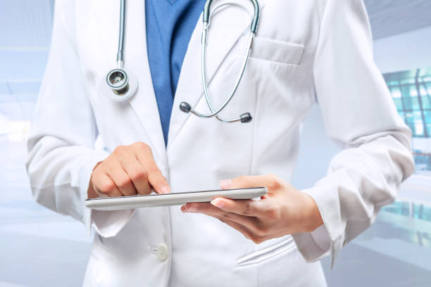istock Woman doctor in white lab coat and stethoscope using tablet 1163656142