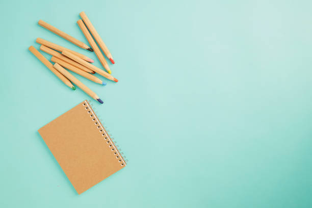 istock Crayon With a notebook on pastel pale blue background 1163659981