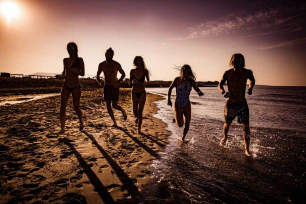 istock Happy friends having fun while running on the beach at sunrise. 1163662792