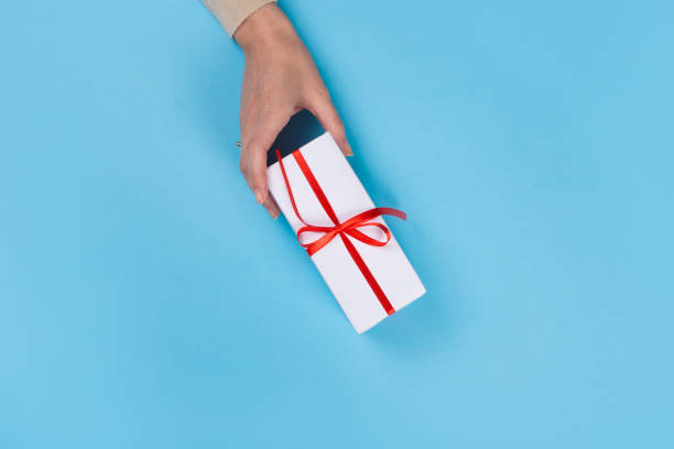 istock Womans hands holding gift or present box on blue pastel table top view. Flat lay  for birthday or New Year. 1163665497