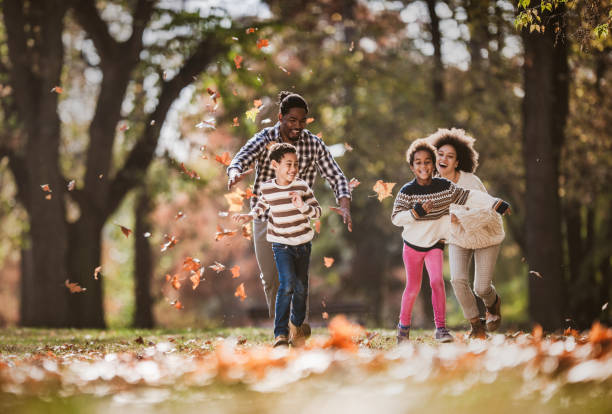 istock Happy black parents having fun while chasing their small kids in autumn day. 1163667364
