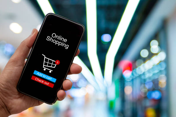 istock Person using smartphone buying and making a payment digitally via application on blur shopping mall background - internet online home shopping concept 1163668659