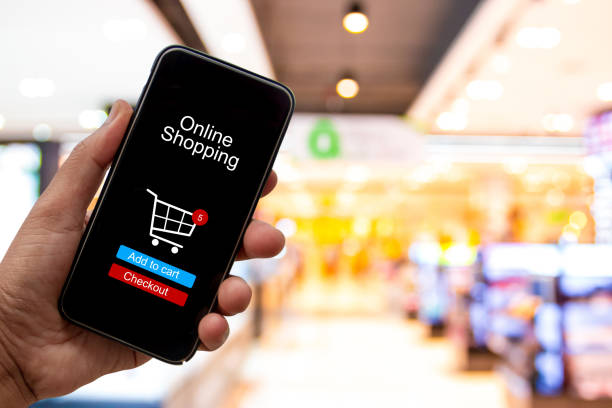 istock Person using smartphone buying and making a payment digitally via application on blur shopping mall background - internet online home shopping concept 1163668694
