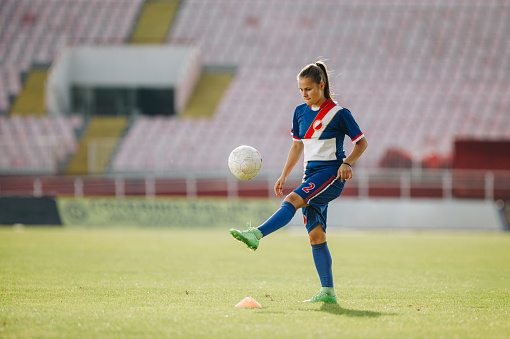 Teenage soccer player kicking the ball on a sports training at stadium. Copy space.