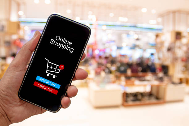 istock Person using smartphone buying and making a payment digitally via application on blur shopping mall background - internet online home shopping concept 1163669952