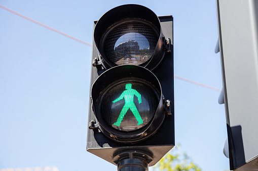 Go sign, green traffic light for pedestrians against clear blue sky background. Pedestrian crossing with safety