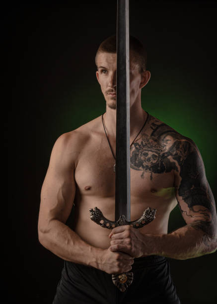 istock muscular guy with bare torso posing on a dark background with a sword 1163673015