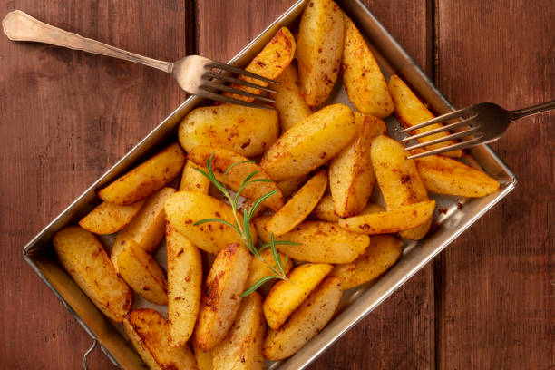 istock Potato wedges, oven roasted with rosemary, in a baking tray on a rustic background, shot from above 1163673052