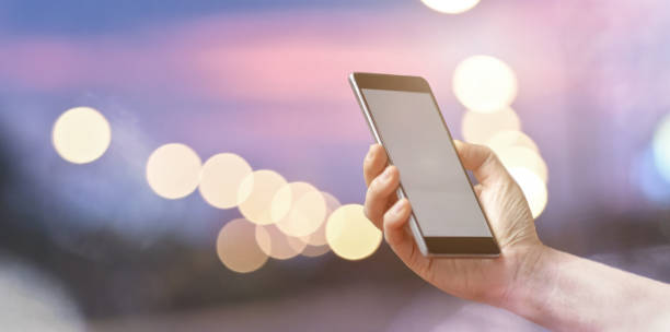 istock Closeup female hand holding mobile smart phone over light bokeh 1163674208