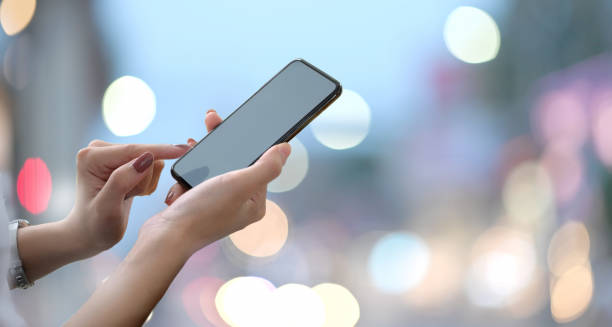 istock Female hands holding blank screen smartphone with blurred bokeh background.