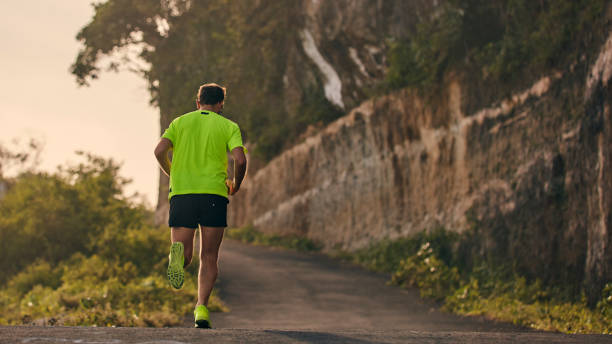 istock Man jogging on a downhill / uphill in suburb mountain road. 1163674366