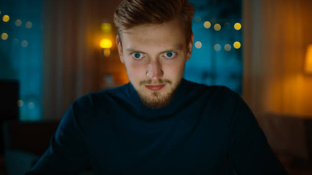 istock In the Evening: Man Sitting at His Desk and Using Laptop. He is Nervous and Fully Concentrated on His Important Job. In the Background Cozy Living Room. 1163674675