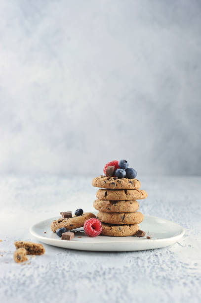 istock Chocolate chip cookies on a plate. Cookies complement the fresh berries of raspberry and blueberry. Free space to place text. 1163674884