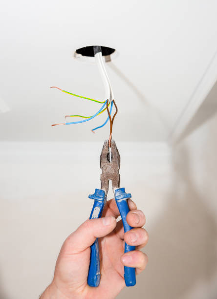 istock Man is holding pliers in his hands. Electrical insulator for light bulb. Adhesive tape for maintenance repair works in the flat. Restoration indoors. 1163676608