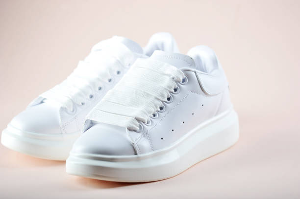 istock White women's sneakers on a light background. Side view. Close-up. 1163678892