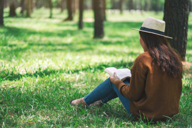 istock A woman reading a book while sitting in the park 1163681277