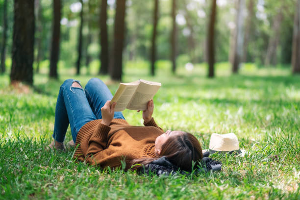 istock A woman lying and reading a book in the park 1163681467