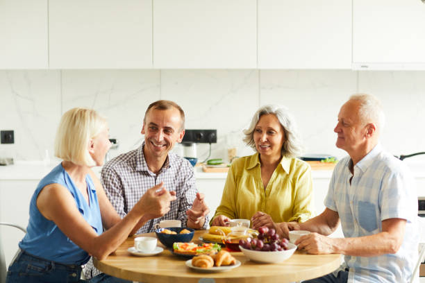 istock Mature Friends Gathered at Kitchen Table 1163685009