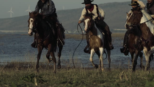 Cowboys with revolver riding horses