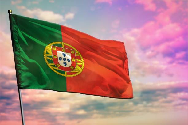 istock Fluttering Portugal flag on colorful cloudy sky background. Prosperity concept. 1163686258