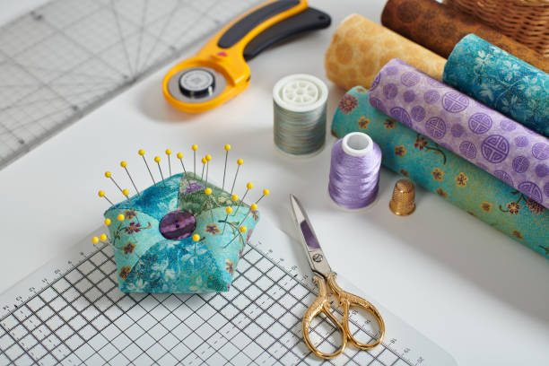 pincushion, craft mat, scissors, rotary cutter, fabric rolls, sewing and quilting accessories - patch textile stack heap imagens e fotografias de stock