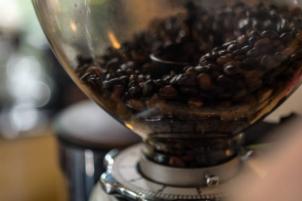 Coffee beans grinder Coffee beans in the  machine grinder with bokeh background. grinding metal power work tool stock pictures, royalty-free photos & images