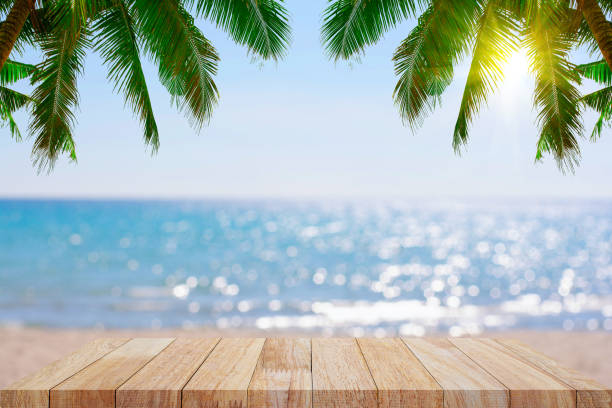 istock Empty wooden planks with blur beach on background, can be used for product placement, palm leaves on foreground 1163689347