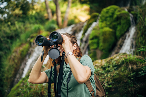 Explorer with binoculars by the waterfall