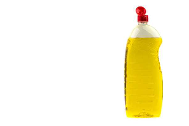 Plastic bottles of dishwashing liquid, glass and tile cleaner, clean plates, a lemon and sponges with an apple tree in blossom on the background. Washing and cleaning concept.