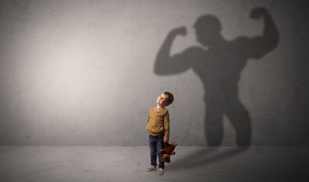 istock Muscleman shadow behind waggish little boy 1163692377