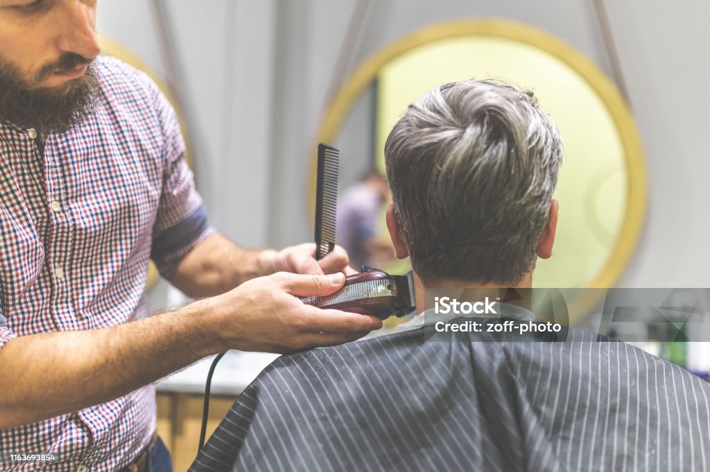 Barber Styling Hair Of His Client In Front Of Mirror By Using Comb And  Clipper At Barbershop Stock Photo - Download Image Now - iStock