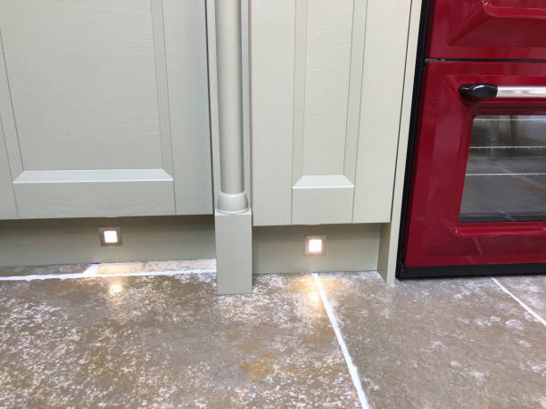 istock Image of spot halogen lights under grey kitchen cabinets / cupboards, floor lighting in interior design of under cabinet LED lighting kit and kitchen plinth lights on kickboards for illumination of oak wooden floorboards vinyl flooring by cooker stove 1163693892