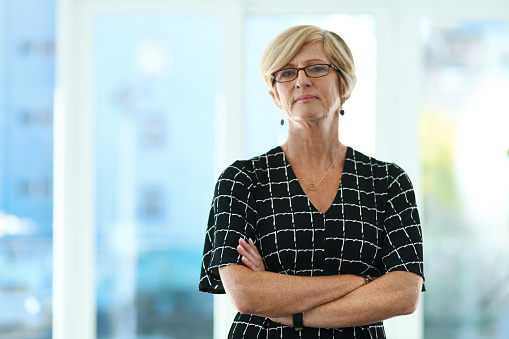 Cropped portrait of a confident mature businesswoman standing with her arms crossed in a modern office