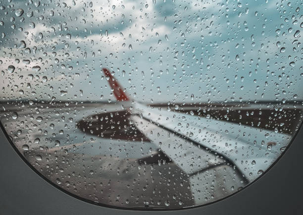 pioggia cadere alla finestra dell'aereo prima di decollare durante la stagione dei monsoni. - runway airport rain wet foto e immagini stock