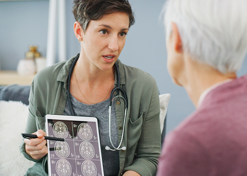 Cropped shot of an attractive young woman showing a senior patient her medical results on a tablet while sitting down