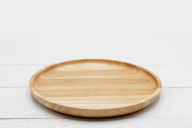 Empty round wooden plate on white wooden table.