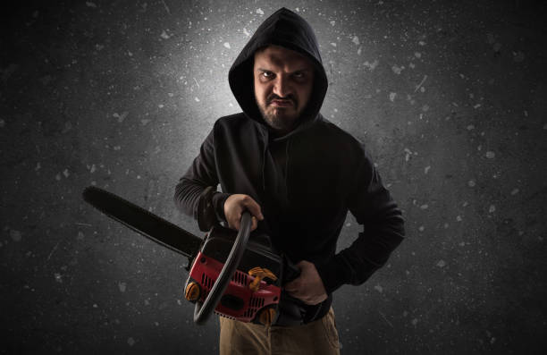Armed villain in an empty dark room Masked armed villain in empty dark room with gun ax chainsaw mallet wrench chainsaw photos stock pictures, royalty-free photos & images