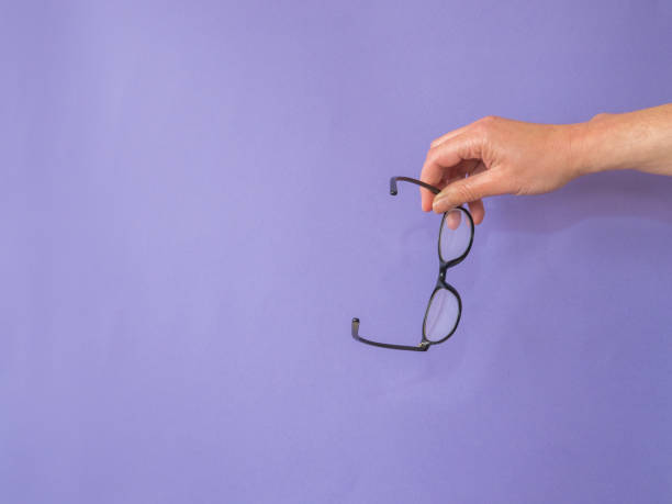 istock Hand with glasses on purple background with copy space 1163700049