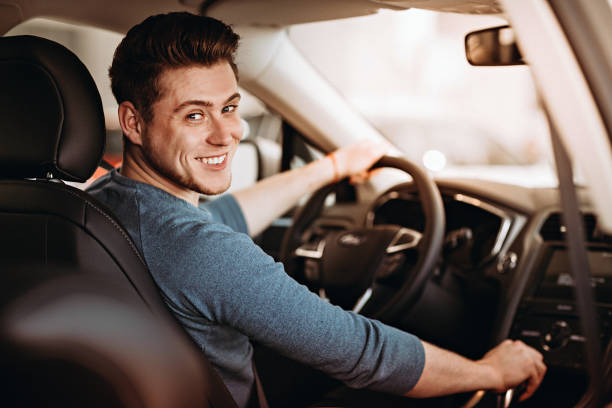 Happy young driver behind the wheel of a car. Buying a car and driving concept. stock photo