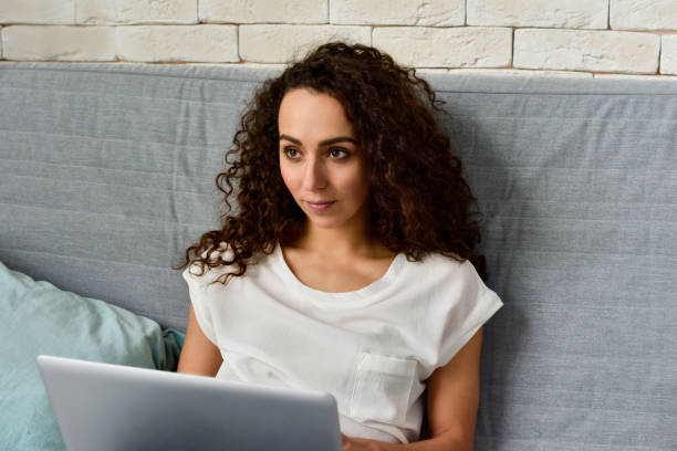 istock Beautiful curly woman with laptop on sofa 1163700175