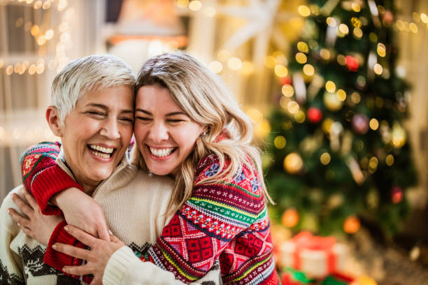 Happy adult daughter embracing her senior mother on New Year's day. Affectionate adult daughter embracing her mature mother on Christmas day at home. new years day photos stock pictures, royalty-free photos & images
