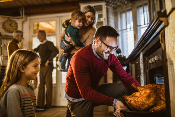 I think this Thanksgiving turkey is baked! Young happy man taking out baked Thanksgiving turkey from the oven for his family's lunch in the kitchen. turkey meat photos stock pictures, royalty-free photos & images