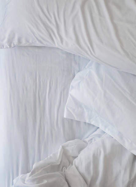 istock Unmade bed close-up with white bedsheet and pillows. 1163701676