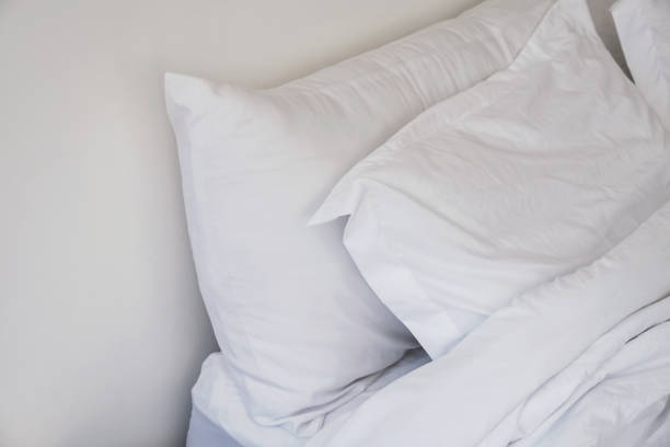 istock Unmade bed close-up with white bedsheet and pillows. 1163701692