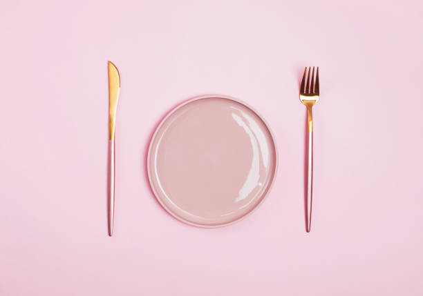 istock Pink plate, fork and knife isolated on pink background 1163702240