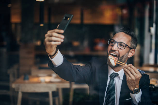 homme d'affaires bel prenant un selfie dans le bar de sushi - eating men food chopsticks photos et images de collection